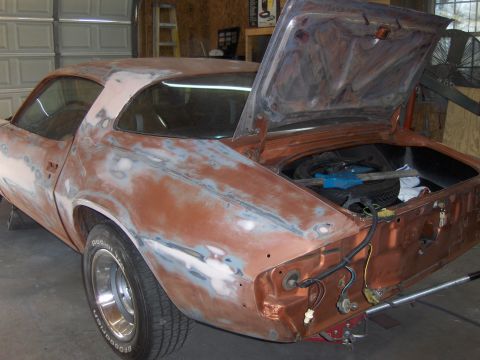 1980 Chevrolet Camaro - This car is undergoing bodywork, with primer showing through the orange paint, and the trunk is open.