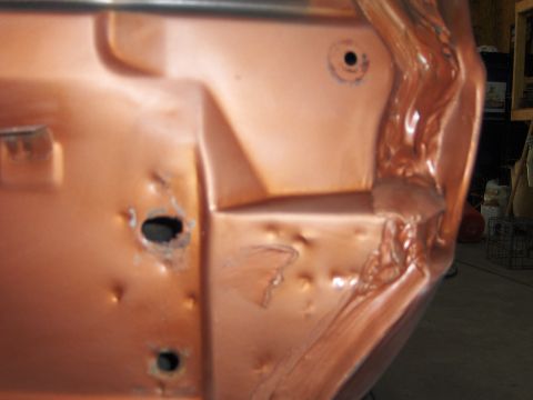 1980 Chevrolet Camaro - Close-up view of a damaged copper-colored car door, revealing dents and structural details.