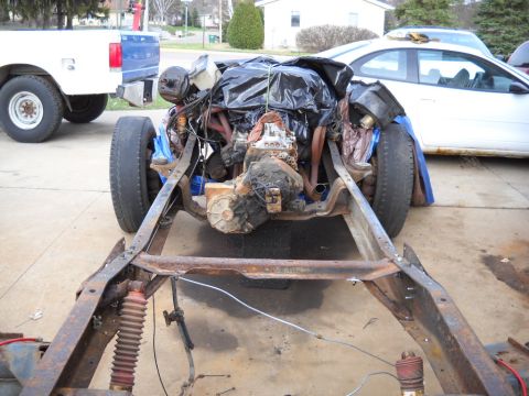 1954 Ford F-100 - The chassis and engine of a 1954 Ford F-100 are visible, with another truck and car in the background.
