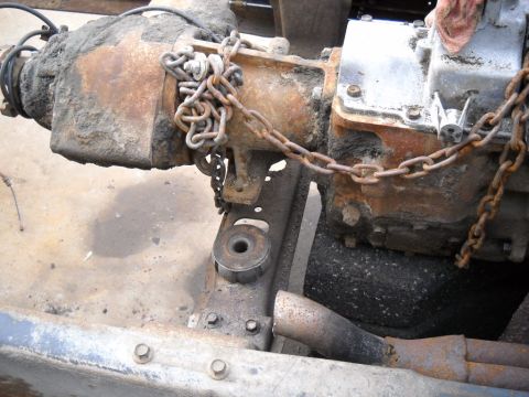 1954 Ford F-100 - Close-up of heavily rusted truck transmission and chassis parts, secured with chains.