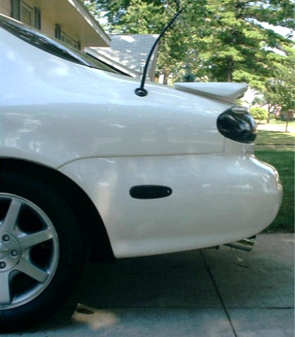 1997 Ford Taurus - Rear view of a white sedan, showing the quarter panel, spoiler, and antenna. The registry claims it is a 1997 Ford Taurus.