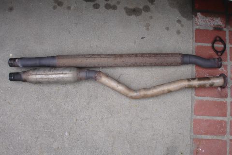 1989 Ford Taurus - Exhaust system components, including a muffler and straight pipe, are shown on a concrete surface.