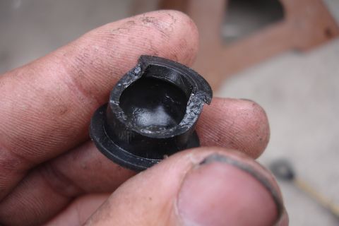 1989 Ford Taurus - A close-up shows a broken black plastic bushing, likely from a vehicle's shifter mechanism, held between dirty fingers.
