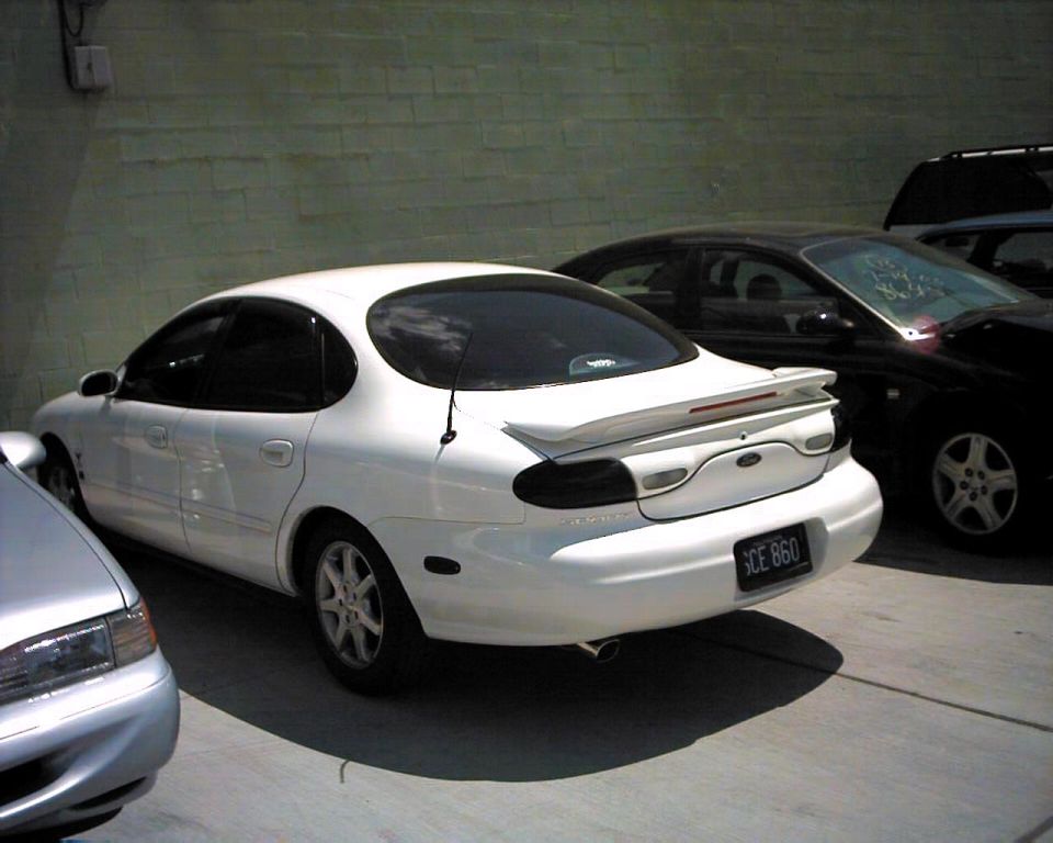 White sedan parked next to a black car. License plate is SCE 860