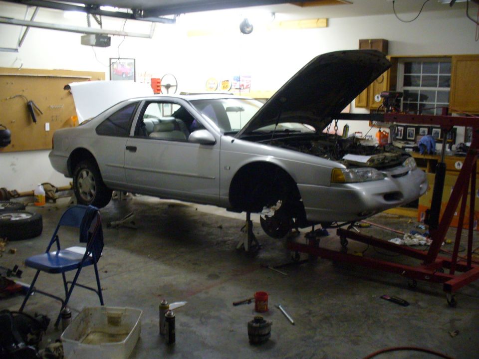 1995 Ford Thunderbird coupe on jack stands with hood open in a garage