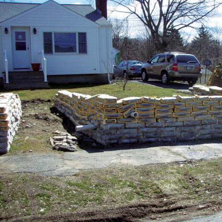 1966 Land Rover Discovery - A tan SUV is parked in the driveway of a white house, with a retaining wall made of sandbags in the foreground.