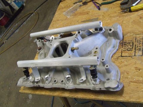 1978 Ford F-250 - Aftermarket fuel injection intake manifold with two fuel rails, resting on a workbench.