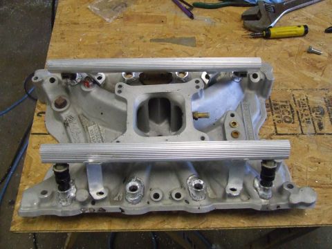 1978 Ford F-250 - An Edelbrock intake manifold with fuel rails is shown on a wooden surface, with tools in the background.
