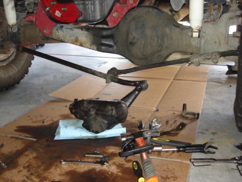 1992 Ford Bronco - The steering and suspension components of a vehicle are shown disassembled on the garage floor.