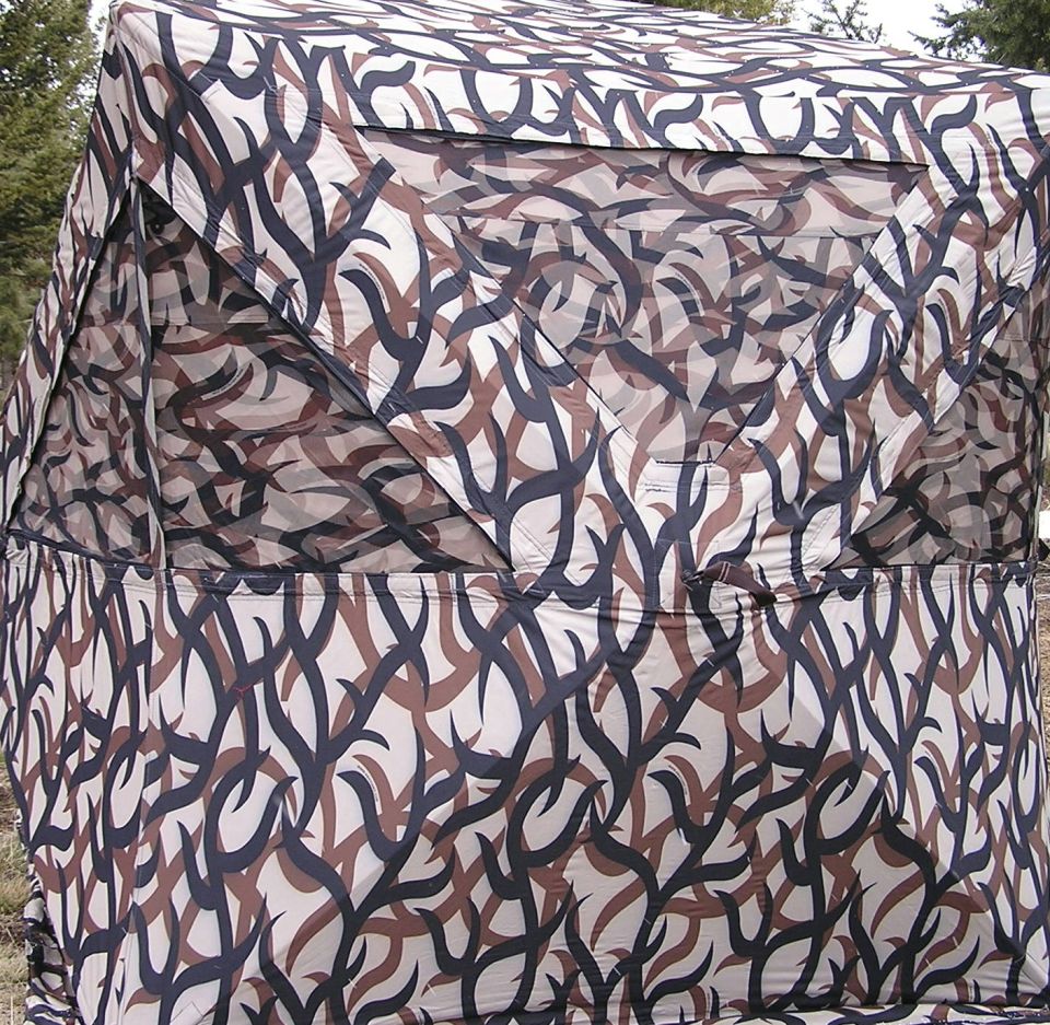 Camouflaged tent with brown, black, and tan abstract pattern, covering a structure