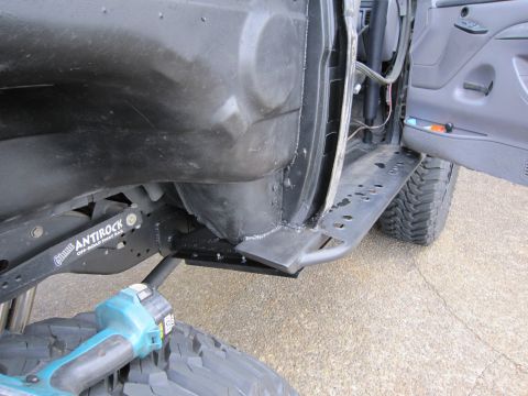 1996 Ford Bronco - Custom rocker panel and suspension components on an off-road vehicle, with a power tool nearby.