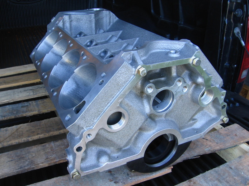 Bare machined V8 engine block inverted on a pallet in a truck bed