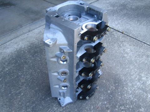 1972 Ford Ranchero - A bare V8 engine block stands upside down on a concrete driveway, showing four black four-bolt main bearing caps secured with gold zinc-pla…