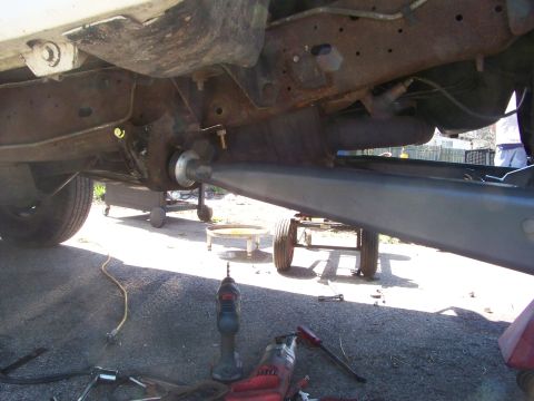 1989 Ford Bronco - Close-up view of the undercarriage of a vehicle, with tools and equipment visible on the ground.