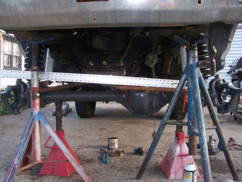 1989 Ford Bronco - Vehicle suspension work in progress, with a measuring tool positioned over the axle.