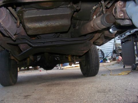 1989 Ford Bronco - The underside of a vehicle is visible, with focus on the drivetrain and rear axle assembly.
