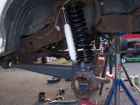 1989 Ford Bronco - Close-up of a vehicle's front suspension during an axle swap, showing a new coil spring and shock absorber.