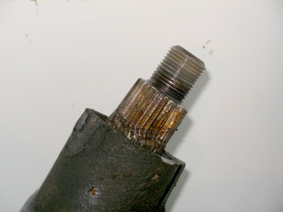 Close-up of a worn splined and threaded shaft end on a rusty part