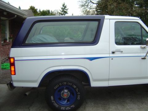 1985 Ford Bronco - The interior of a van, stripped down to reveal the cargo floor and seating area.
