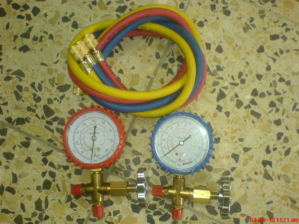 Qing Xin A/C manifold gauge set with red, blue and yellow charging hoses on tile