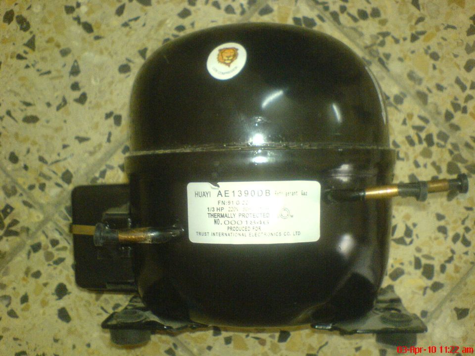 Black Huayi AE1390DB hermetic compressor with copper tubes on a tile floor