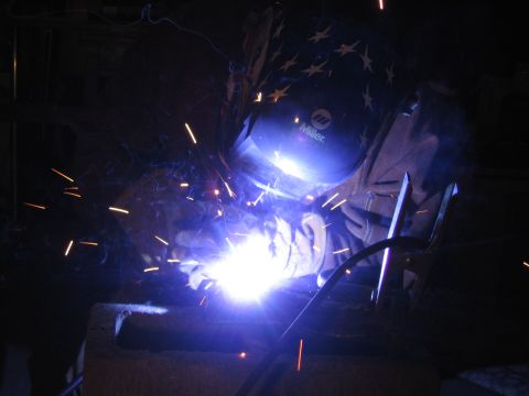 1989 Ford Bronco - A welder works in a dark environment, illuminated by the bright sparks from their torch.
