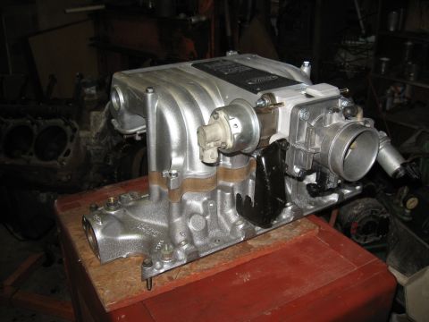1994 Ford Bronco - Close-up of a Ford intake manifold assembly, likely for a performance engine, with other engine parts in the background.