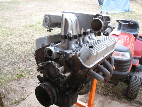 1994 Ford Bronco - A V8 engine is mounted on an orange stand, with a red riding mower visible in the background.