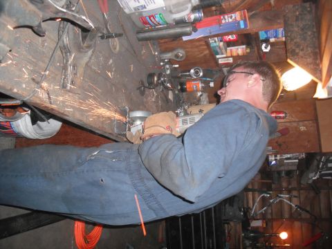 1991 Ford Bronco - Workshop scene with a person grinding metal, sparks flying.