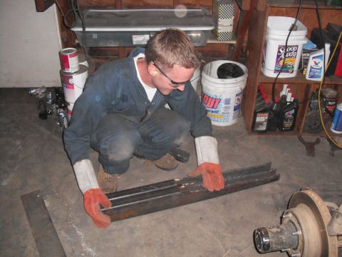 1991 Ford Bronco - A person works on metal components in a cluttered garage setting.