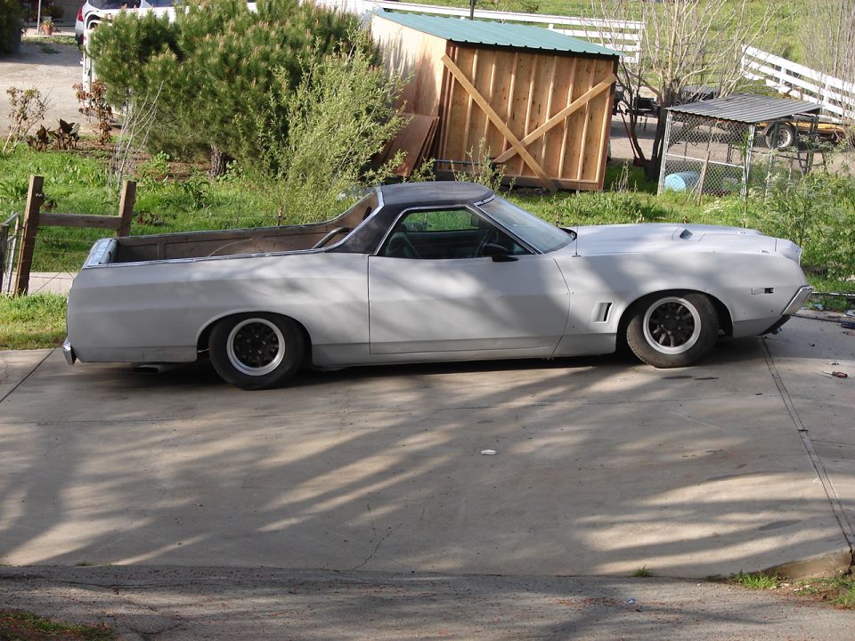 Light gray 1973 Ford Ranchero pickup truck, side view, black top, custom wheels