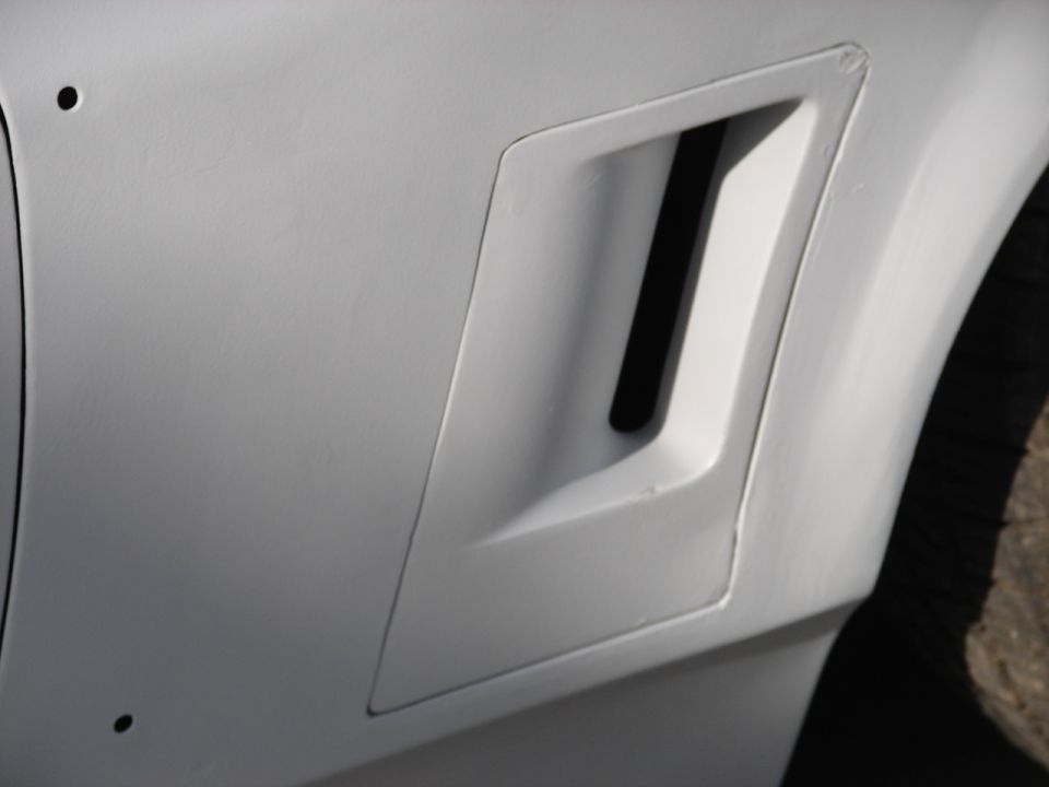 close-up of a white car's fender with a black vent