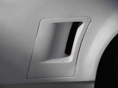 1973 Ford Ranchero - Detail of a white car's fender vent, showing its angular design and textured surface.