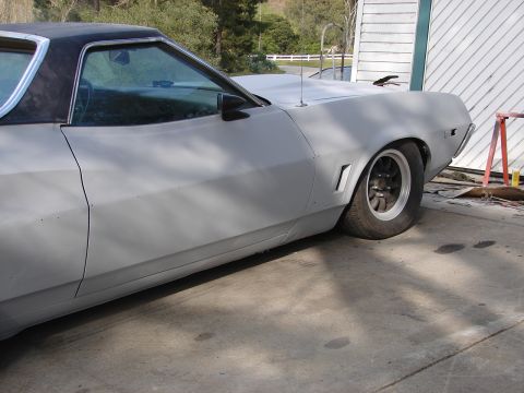 1973 Ford Ranchero - Primer gray 1973 Ford Ranchero with a black vinyl top and custom wheels sits outside.