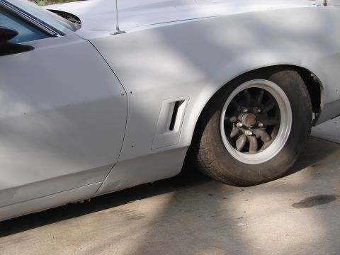 1973 Ford Ranchero - The side of a white vehicle, likely a 1972 Ford Ranchero, shows a unique fender vent and a custom wheel.