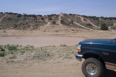 1995 Ford Bronco - A 1995 Ford Bronco is parked in a dry, hilly terrain with a clear blue sky overhead.