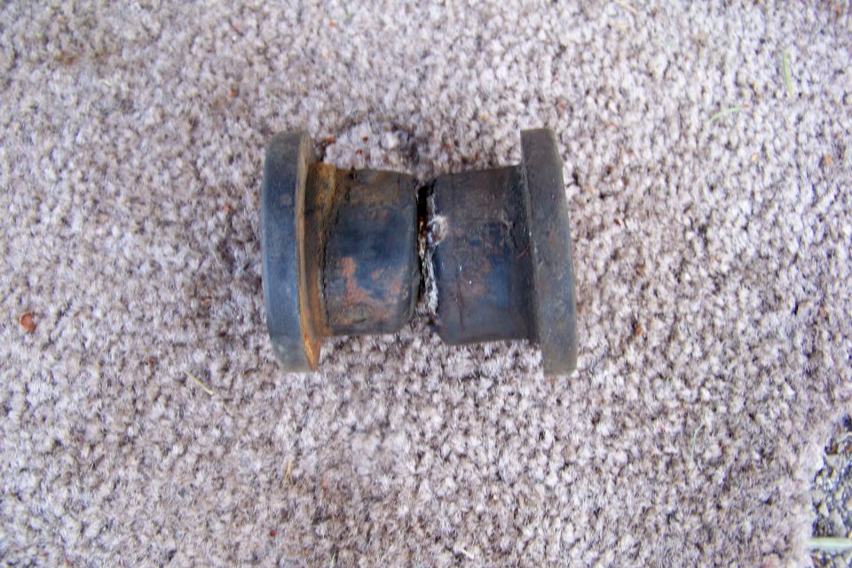 Rusty metal axle part with flanges on a carpeted surface