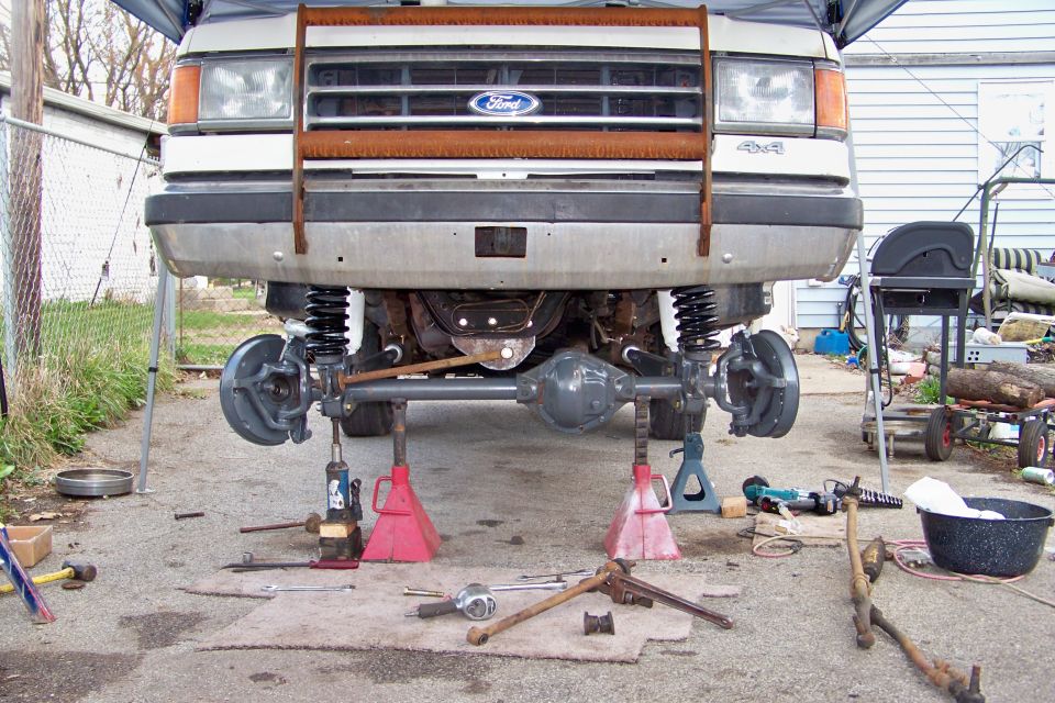 1989 Ford Bronco front axle on jack stands, 4x4 badge visible