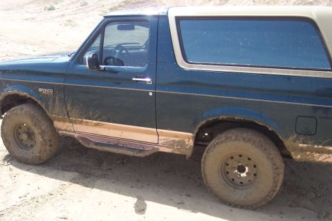 1995 Ford Bronco - Mud-covered 1995 Ford Bronco parked on a dirt road.