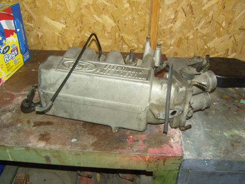 2007 Ford Mustang - A cast aluminum Ford EFI upper intake manifold sitting on a paint-spattered workbench, with 'Ford Electronic Fuel Injection' cast into the…