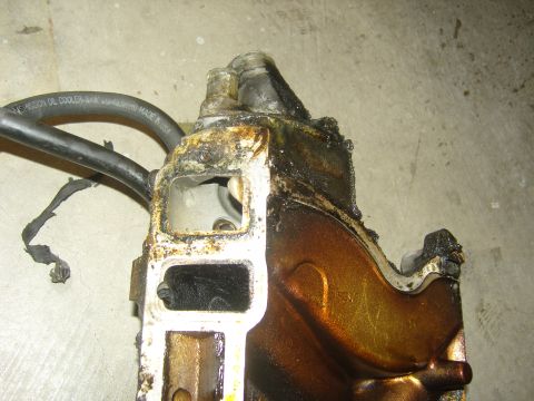 2007 Ford Mustang - Close-up of a heavily used engine intake manifold part with a transmission oil cooler hose.
