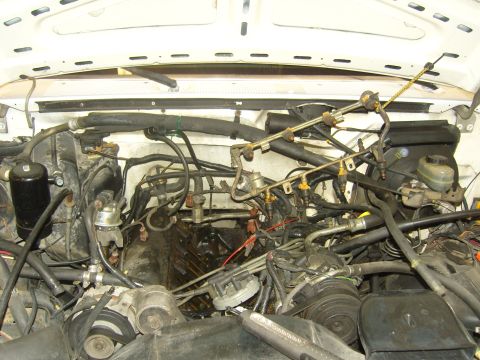 2007 Ford Mustang - The engine bay of a vehicle, showing various hoses, wires, and mechanical components.