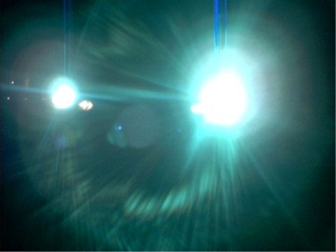 1997 Ford Taurus - Bright headlights create a strong lens flare effect, obscuring any vehicle details. The Supermotors logo is visible at the bottom.