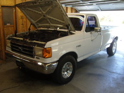 2007 Ford Mustang - A white Ford F-250 full-size pickup truck parked inside a wood-framed garage, shown from a 3/4 front angle with the hood raised. It has chr…