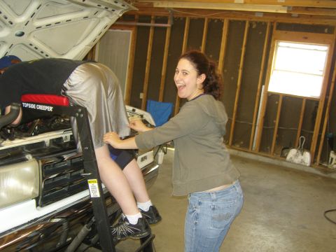 2007 Ford Mustang - A person works on the engine of a white 1987 Ford F-150 truck in a garage.