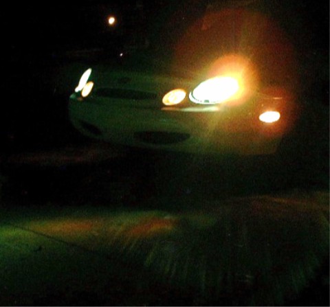 1997 Ford Taurus - The front of a 1997 Ford Taurus is visible at night, with its headlights illuminated.