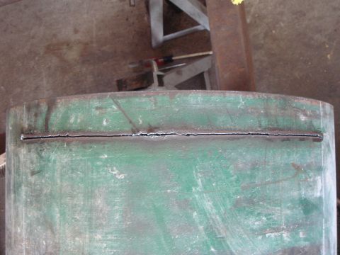 1992 Ford Bronco - Close-up of a damaged green metal pipe with a visible crack along its length.