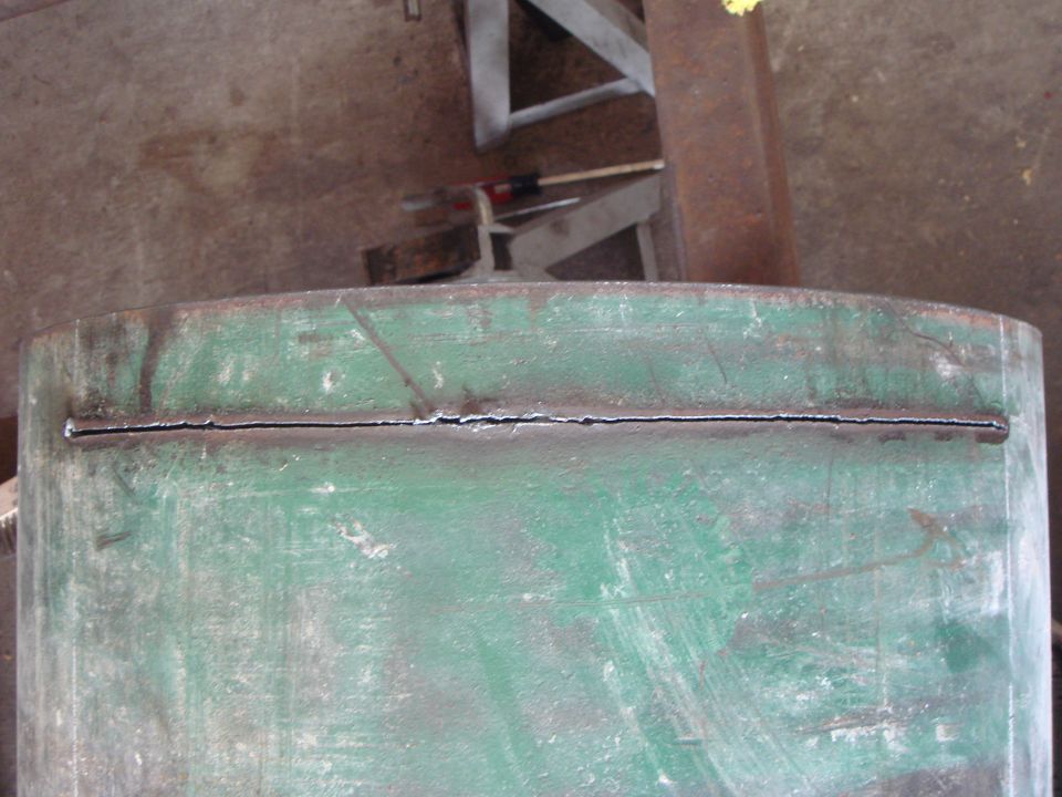 Green metal pipe with a long crack down the middle, showing signs of wear and tear