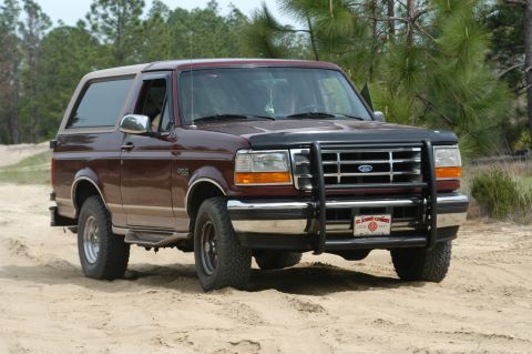 1996 Ford Bronco - This maroon 1996 Ford Bronco is shown in a three-quarter front view, equipped with a brush guard and off-road tires.