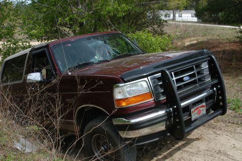 1996 Ford Bronco - This 1996 Ford Bronco is parked on a dirt path surrounded by brush and trees.